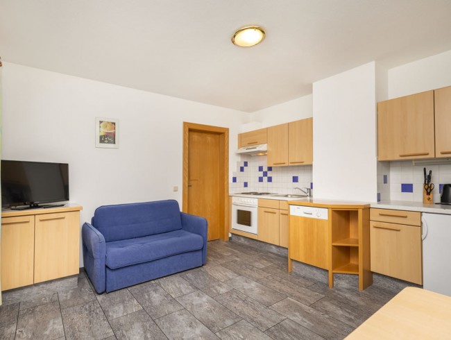 Wohnküche mit Couch und Flat-TV im Appartement 1
