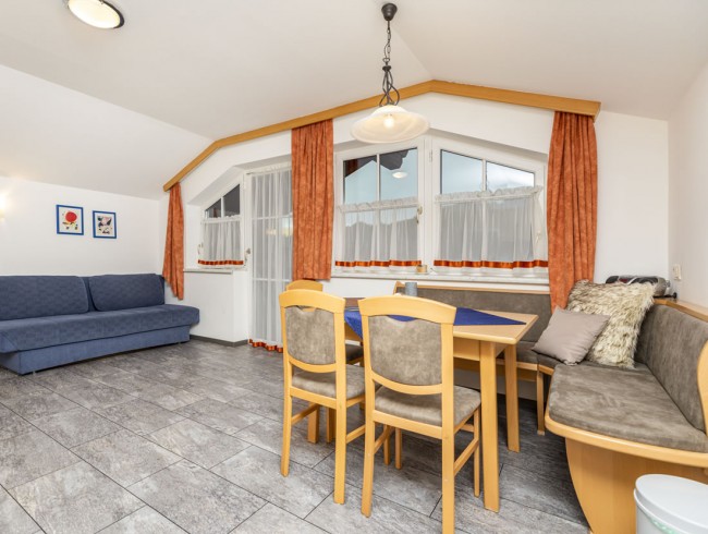 Wohnküche mit Essecke, Couch und Balkon im Appartement 3